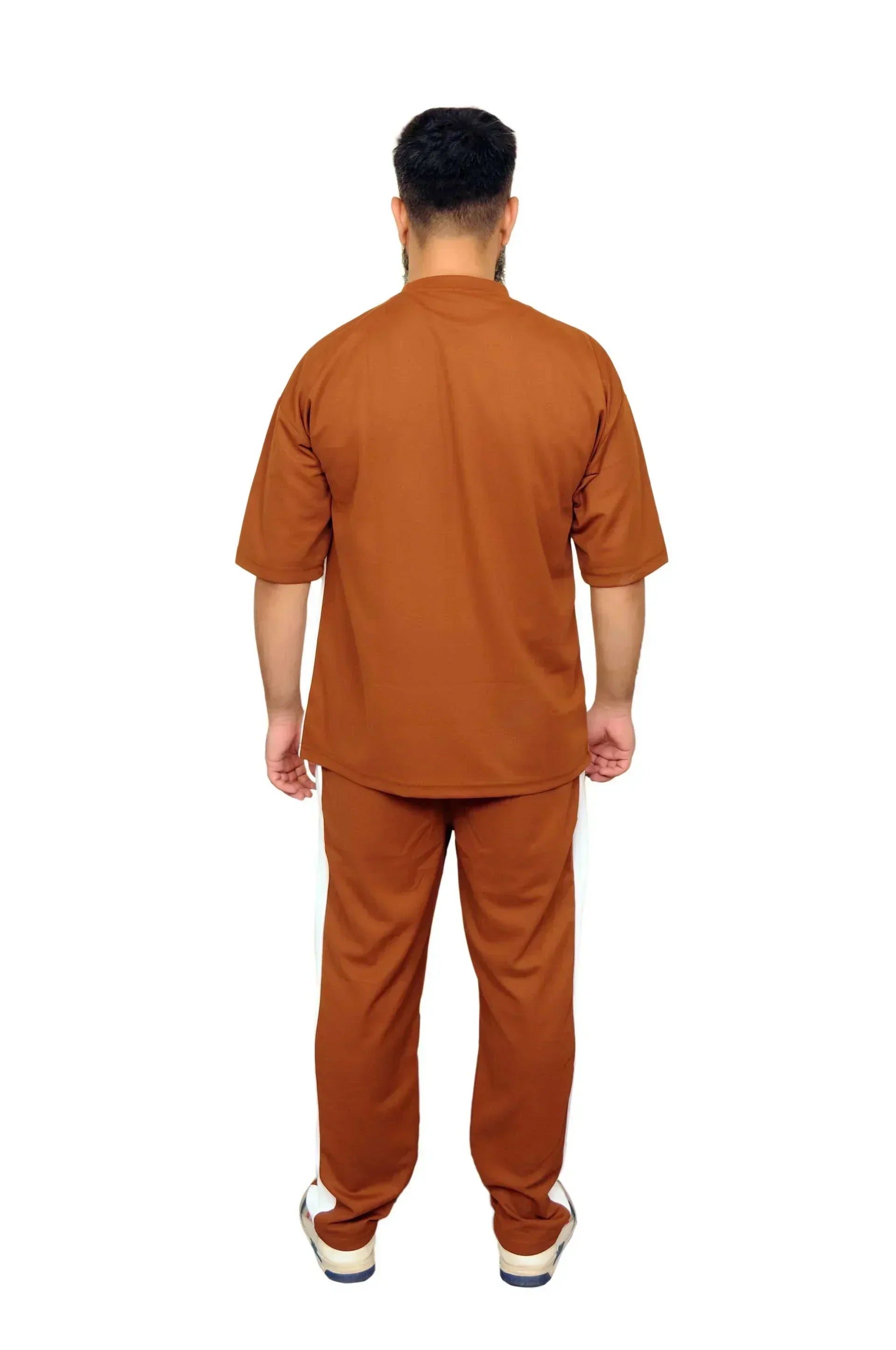 Man wearing brown short-sleeve shirt and matching pants standing against white background