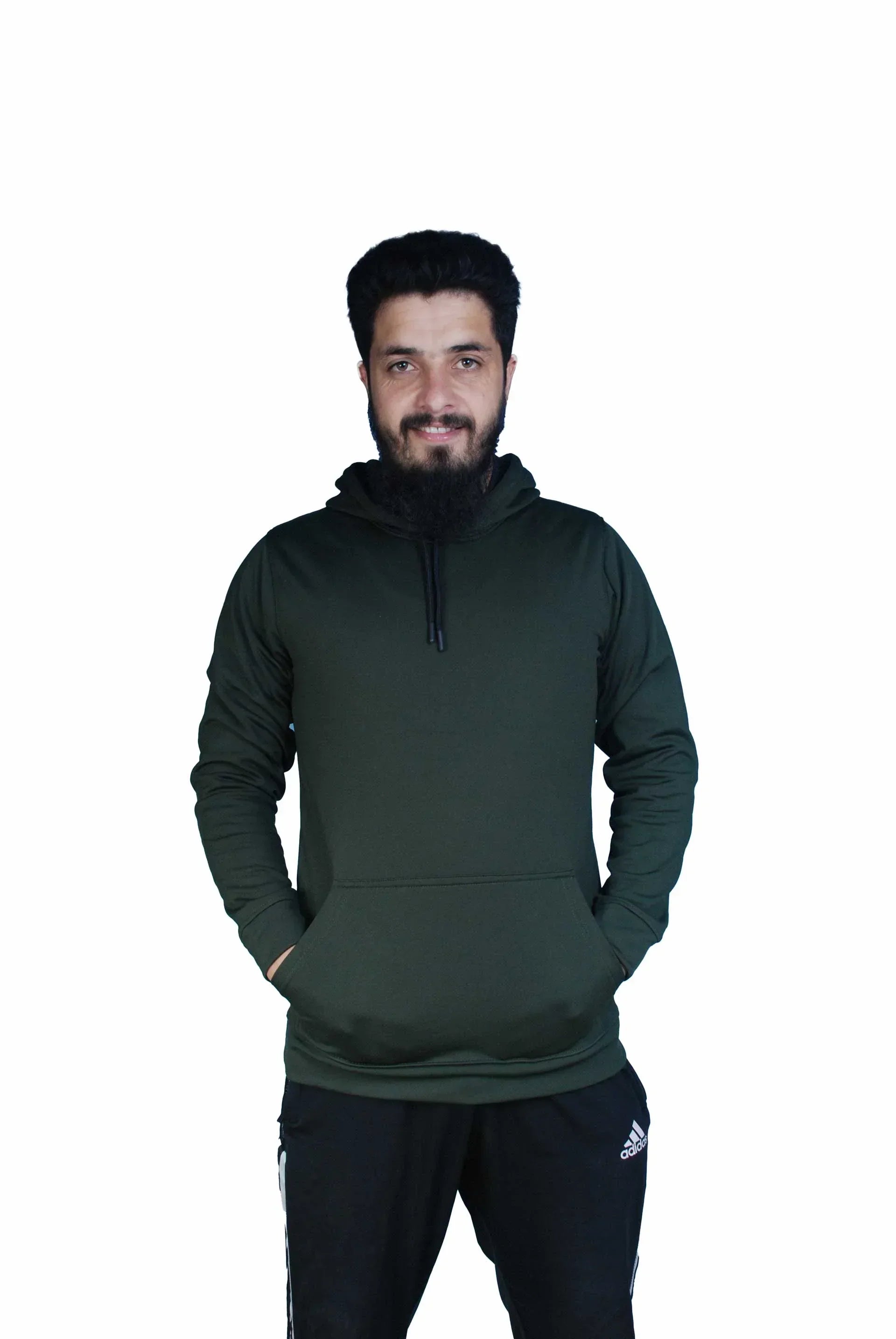 Man in dark green hoodie with front pocket and black Adidas track pants smiling