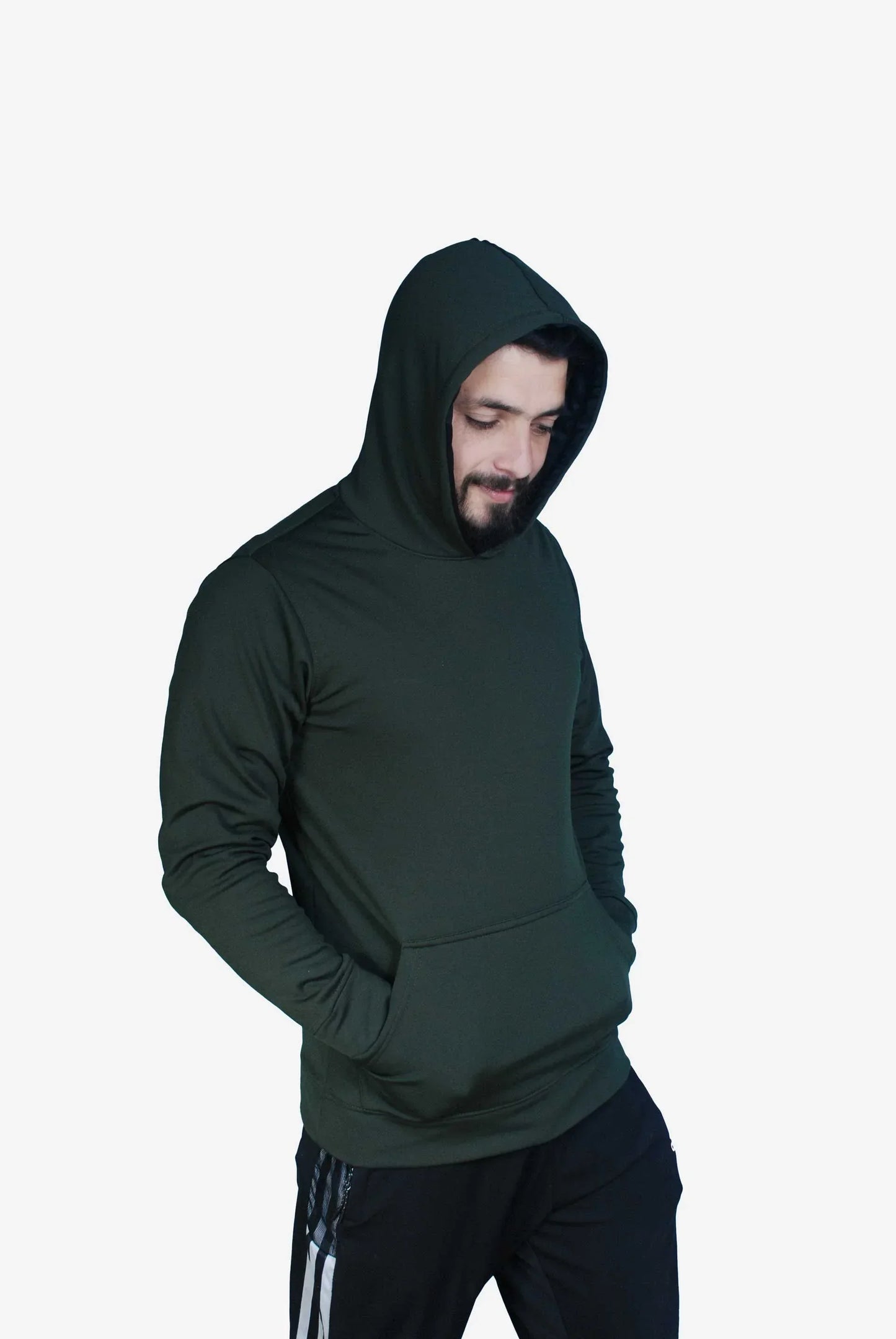 Man wearing dark green hooded sweatshirt with hands in pocket and black athletic pants