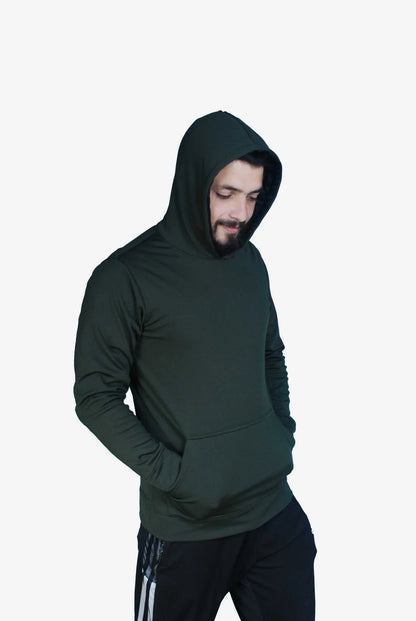 Man wearing dark green hooded sweatshirt with hands in pocket and black athletic pants