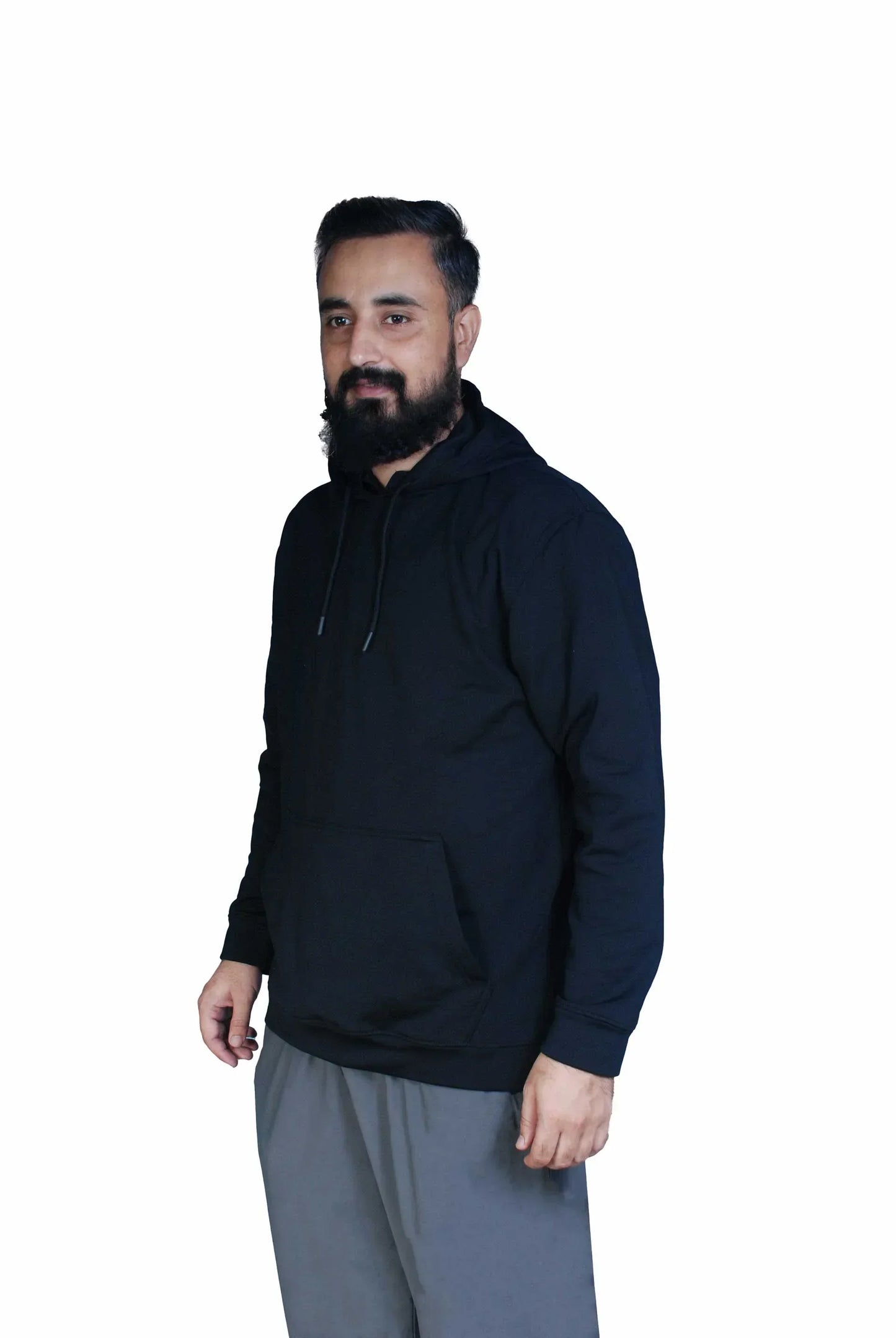 Man with beard wearing black hoodie and gray pants on white background