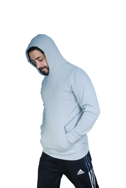 Man wearing light gray hoodie and black Adidas track pants against white background